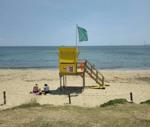 Yellow lifeguard station on a sunny Spanish beach with people enjoying the summer day.