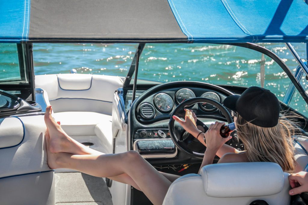 A woman enjoys a sunny day on a luxury boat, relaxing with a beverage.