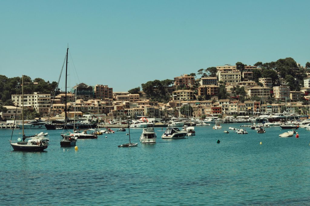 Scenic harbor view with sailboats and urban backdrop in sunny Spain.