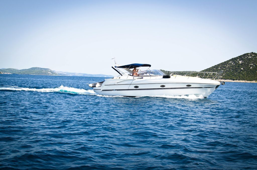 A sleek white yacht cuts through the open sea under a clear blue sky, capturing relaxation and travel.